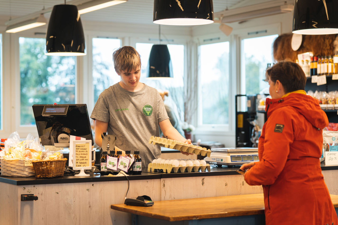 Bildet viser en elev som selger egg til en kunde.